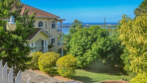A house with a view of the ocean, surrounded by lush greenery and a clear blue sky. - The Shallhome  (Montego Bay)