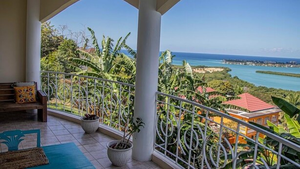 A balcony with a view of the ocean and a tropical landscape. - The Shallhome  (Montego Bay)