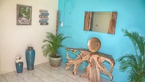 A room with a blue wall, a wooden console table, two large vases, a potted plant, a framed picture, and a mirror. - The Shallhome  (Montego Bay)