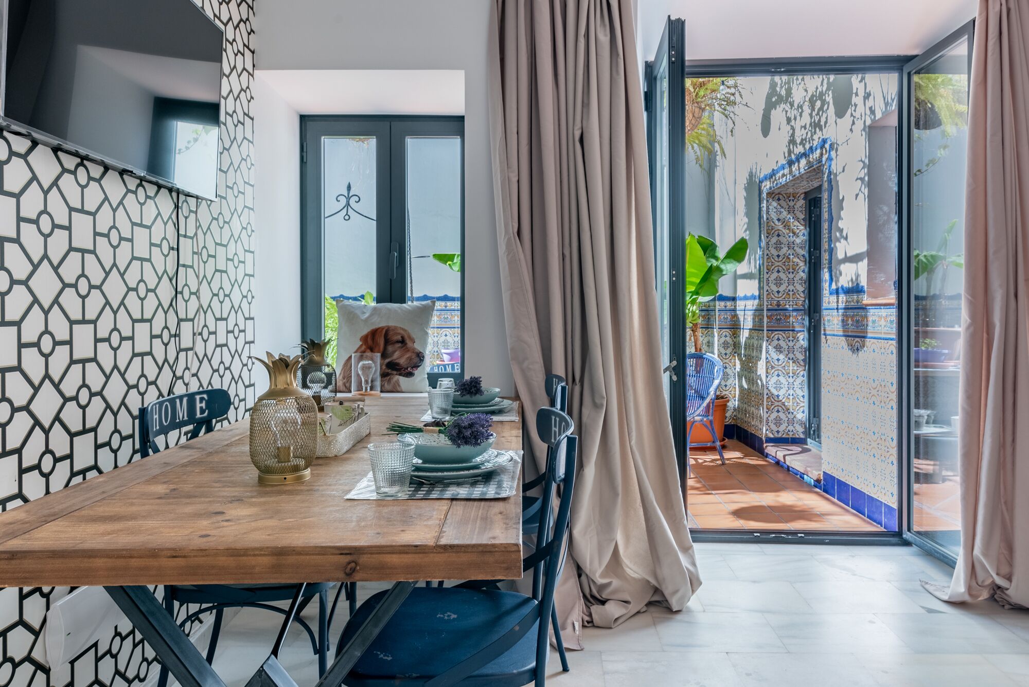 Un comedor con una mesa de madera, sillas y vista del patio exterior.