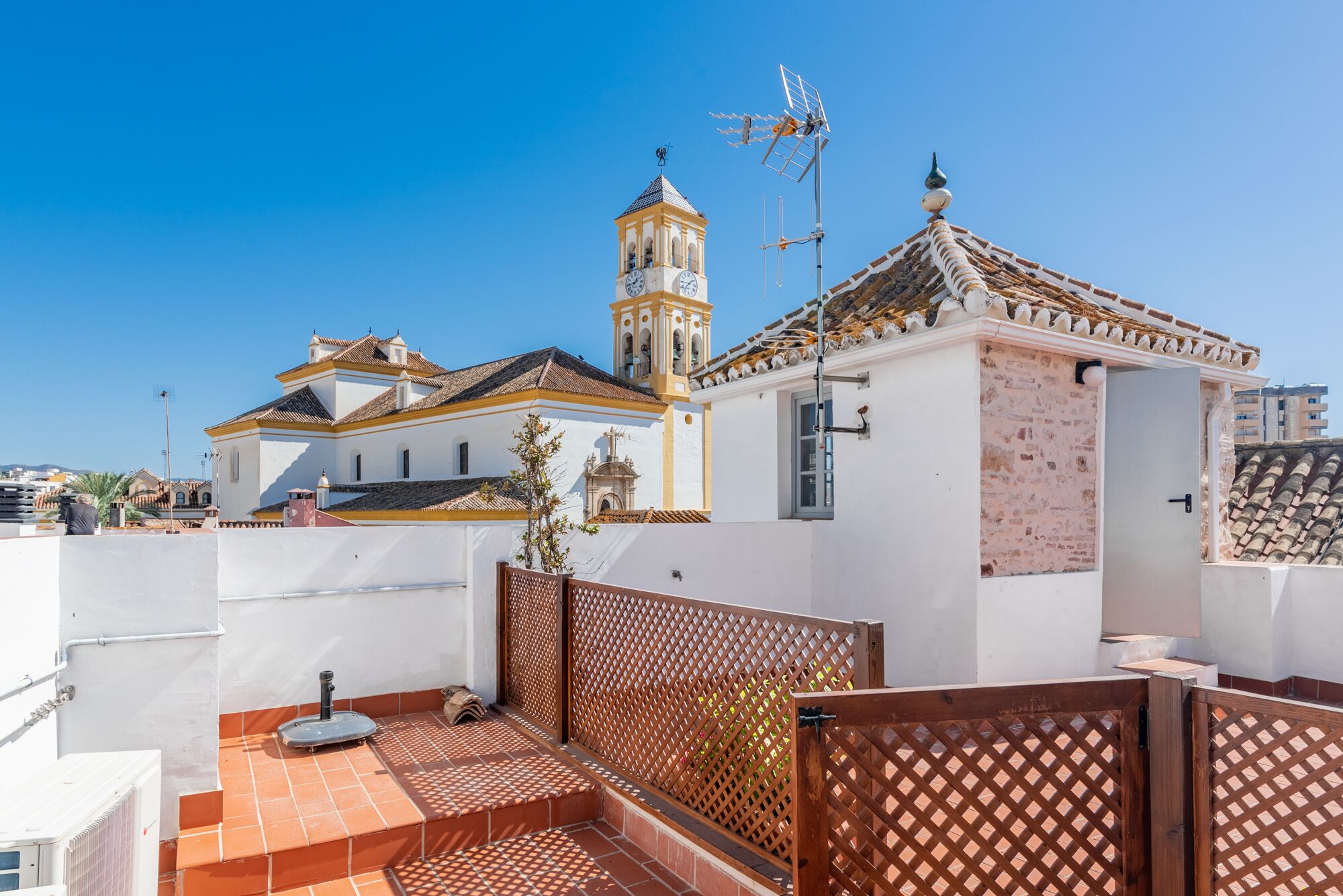 Un edificio con una torre dell'orologio, un piccolo campanile e una veletta.