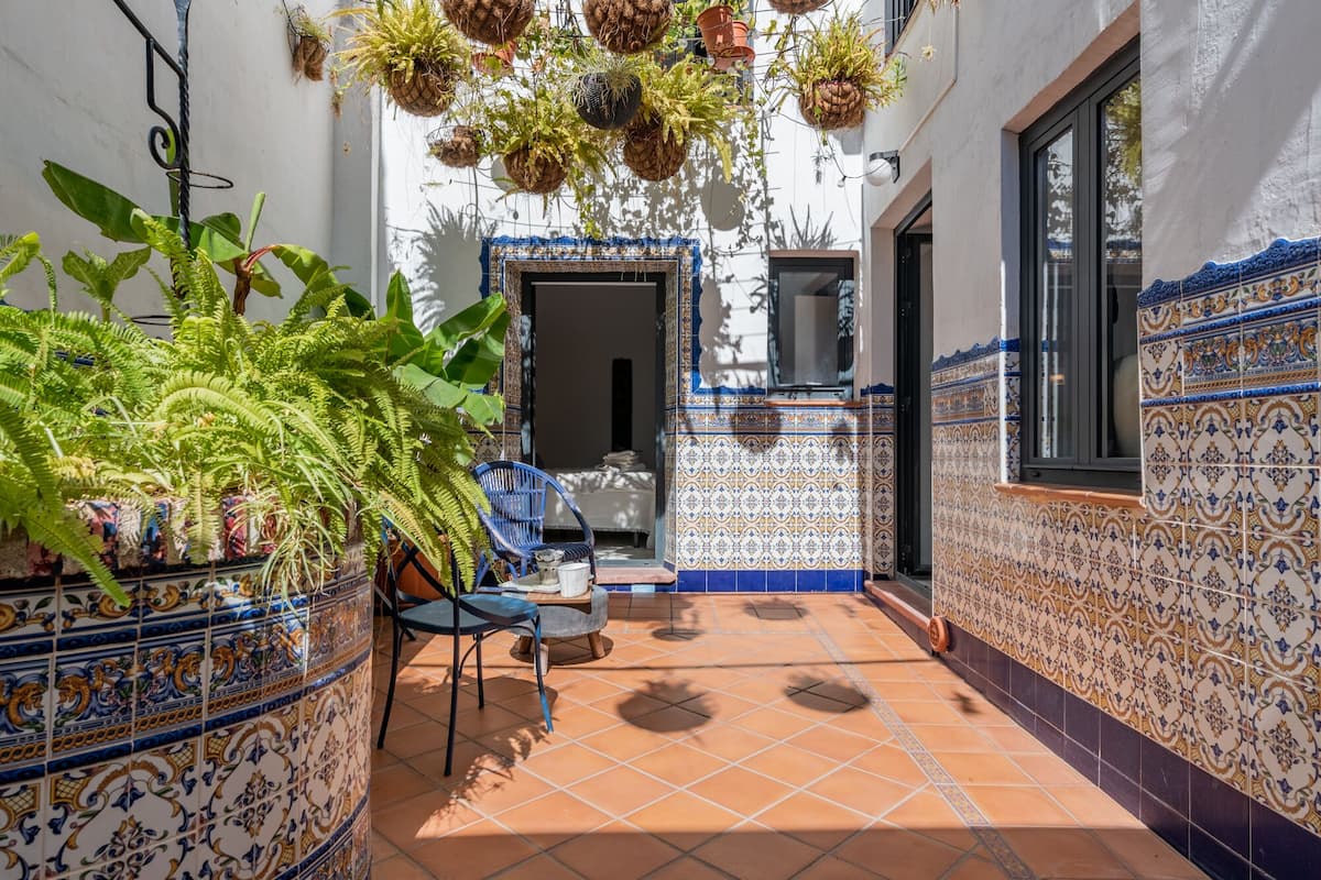 Une cour avec des jardinières suspendues, un sol carrelé et une chaise bleue.