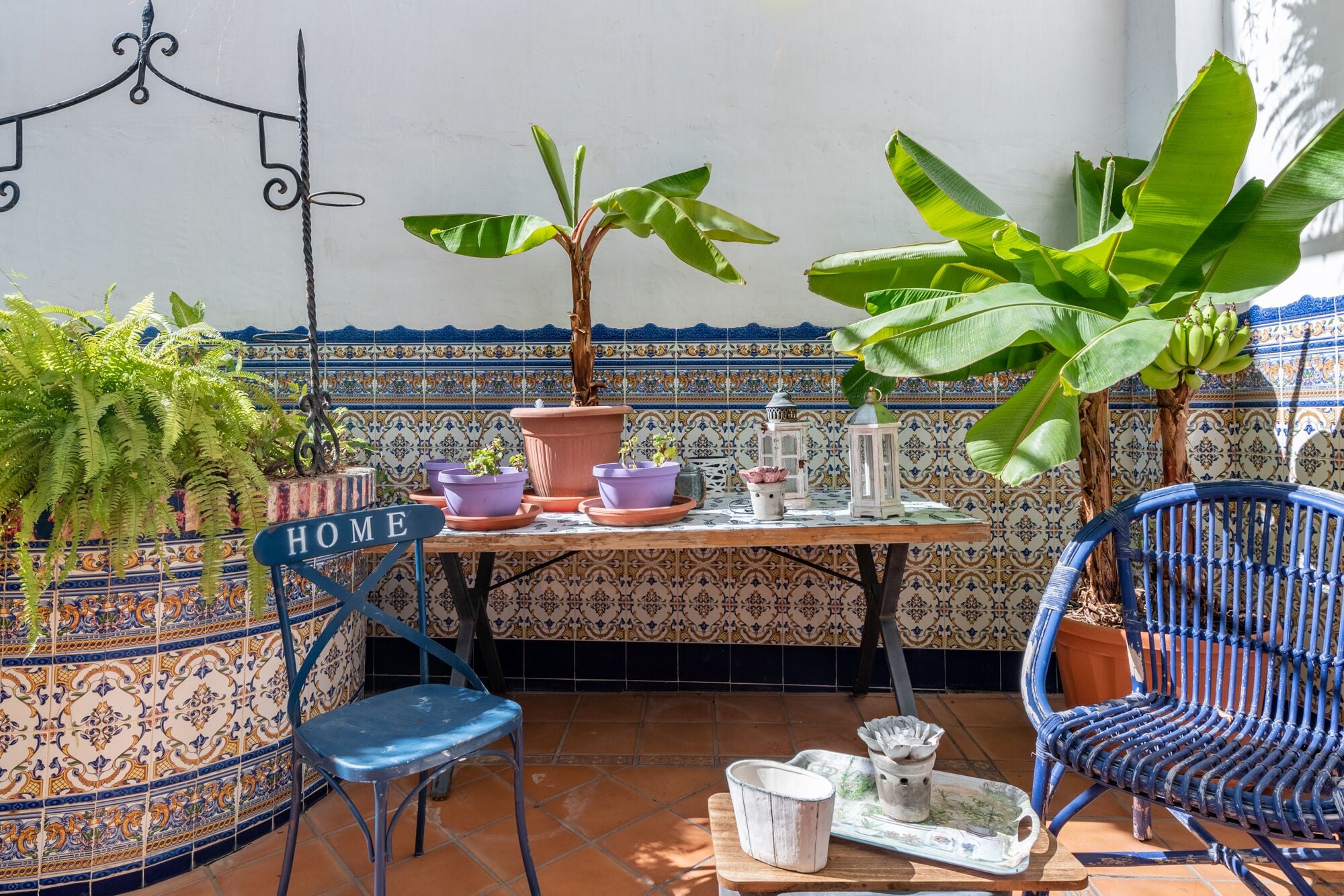 Eine Terrasse mit Tisch, Stühlen, Topfpflanzen und einem dekorativen Schild.