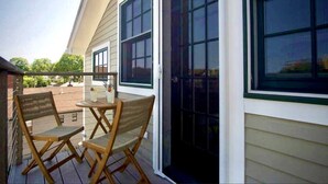 A covered patio with a table and chairs, large windows, and a door. - "Meteor": River View Penthouse in Downtown Mystic (Mystic)