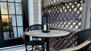 A covered patio with a round table and two chairs, a lantern, and a lattice screen. - "Shepherdess": Mystic Blue Salon With River View (Mystic)