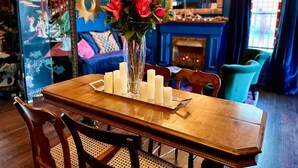 A dining area with a wooden table, chairs, and a vase with red flowers. - "Shepherdess": Mystic Blue Salon With River View (Mystic)