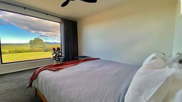 A bedroom with a bed, a ceiling fan, a window with a view of a landscape, and a red throw blanket.