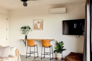 Una sala de estar moderna con comedor, televisor de pantalla plana y ventilador de techo.