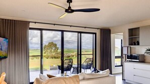 A modern bedroom with a large window, a ceiling fan, and a view of the outdoors. - Wamoon Retreat - The Apartment ~ Luxury Gateway to Wilsons Prom (Yanakie)