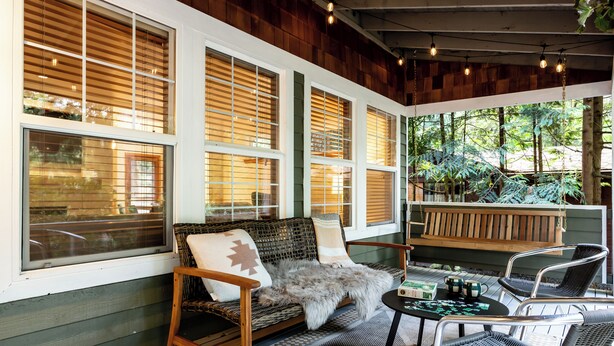 A cozy outdoor seating area with wicker furniture, a wooden bench, and a table with a board game.