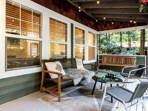 A cozy outdoor seating area with wicker furniture, a wooden bench, and a table with a board game. - Charming cozy cottage in beautiful surroundings minutes from outdoor adventures. (Bellingham)