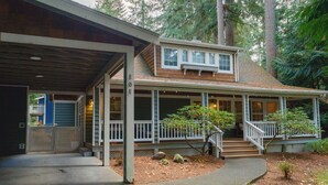 A two-story house with a covered porch, a small garden with rocks and plants, and a staircase leading to the upper floor.