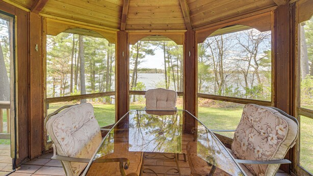 A covered outdoor seating area with a glass table and two upholstered chairs. - Lakefront Chetek Haven: Dock, Screened Gazebo (Chetek)