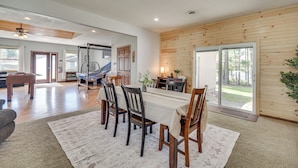 A spacious dining area with a long table, wooden chairs, and a view of the outdoors. - Lakefront Chetek Haven: Dock, Screened Gazebo (Chetek)