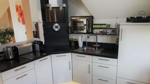 Eine moderne Küche mit weißen Schränken, einer schwarzen Arbeitsplatte, einem Einbauofen, einer Kaffeemaschine und einem Spülbecken.