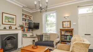 A living room with a fireplace, a television, a bookshelf, and a comfortable seating area. - 3 Hamilton Terrace (Harrogate)