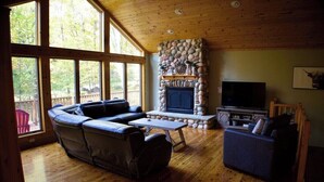 Una sala de estar acogedora con chimenea de piedra, sofás de cuero y un televisor.