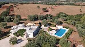 Vue aérienne d’une propriété comprenant une piscine, plusieurs bâtiments et des champs environnants.