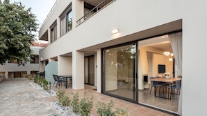 A modern building with a patio area, outdoor seating, and a glass door leading to an interior space. - Aelia - Vacation house with private pool in Kounoupidiana, Crete (Kounoupidianá)