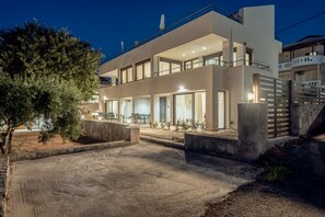 Une maison moderne à deux étages, dotée d’un balcon, d’une allée et d’un arbre au premier plan.