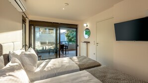 A hotel room with two beds, a TV, a sliding glass door to a balcony, and a ceiling-mounted air conditioner. - Iris - Vacation house with private pool in Kounoupidiana, Crete (Kampáni)
