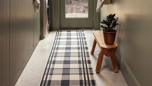 A narrow hallway with a checkered rug, a wooden bench, a potted plant, and a door leading to an outdoor area with trees. - The Lark Haus: Luxury Home with stunning lake view (Elizabeth)