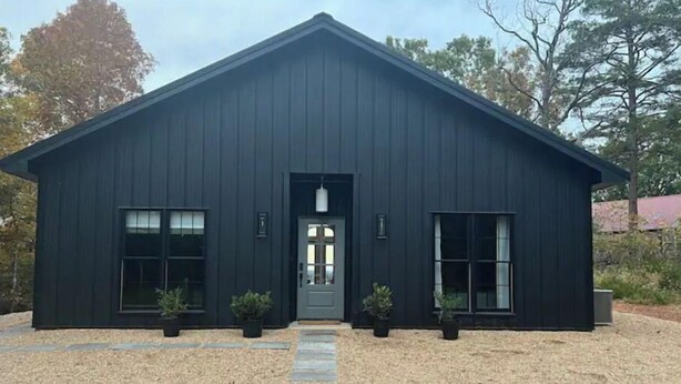 A modern, dark-colored building with a symmetrical facade, a central entrance, and potted plants at the entrance. - The Lark Haus: Luxury Home with stunning lake view (Elizabeth)