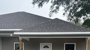 A single-story house with a front porch, a white door, and two windows.
