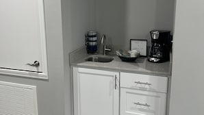 A kitchen with a sink, a coffee maker, and a bowl on the counter.