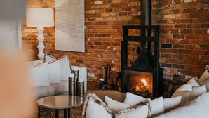Una sala de estar acogedora con pared de ladrillo, chimenea, sofá y mesa de centro.