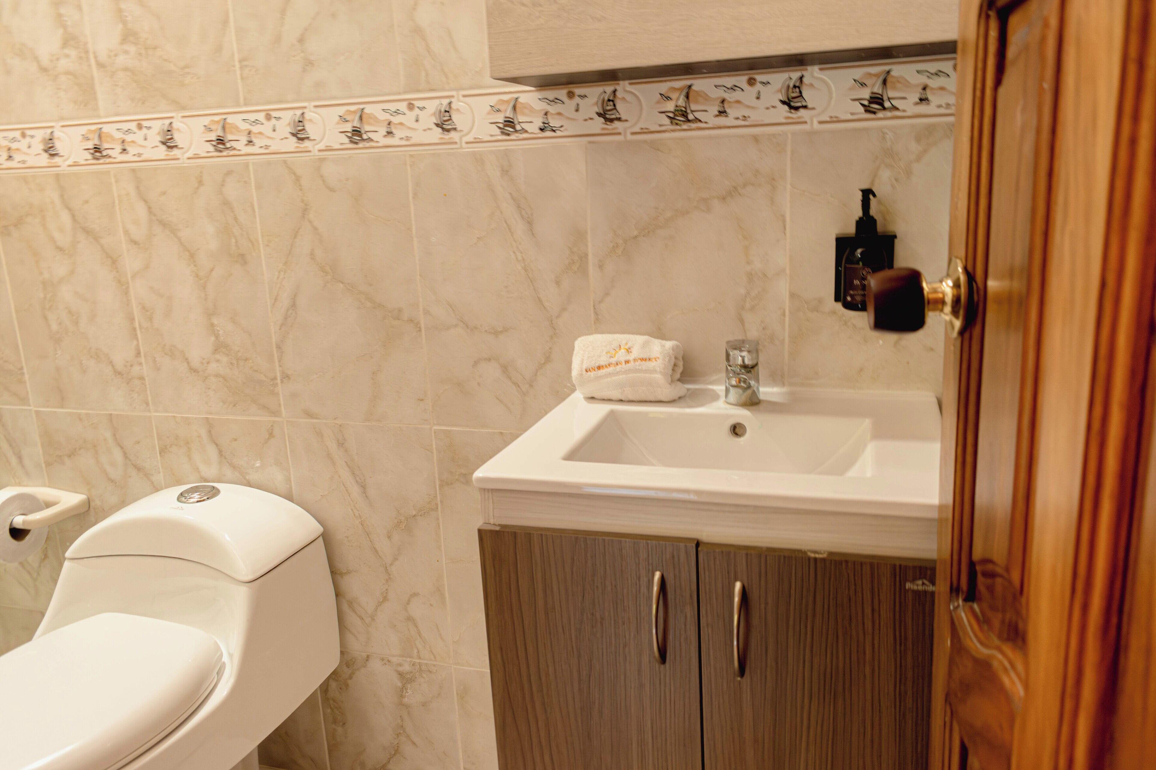 A bathroom with a toilet, sink, and cabinet.