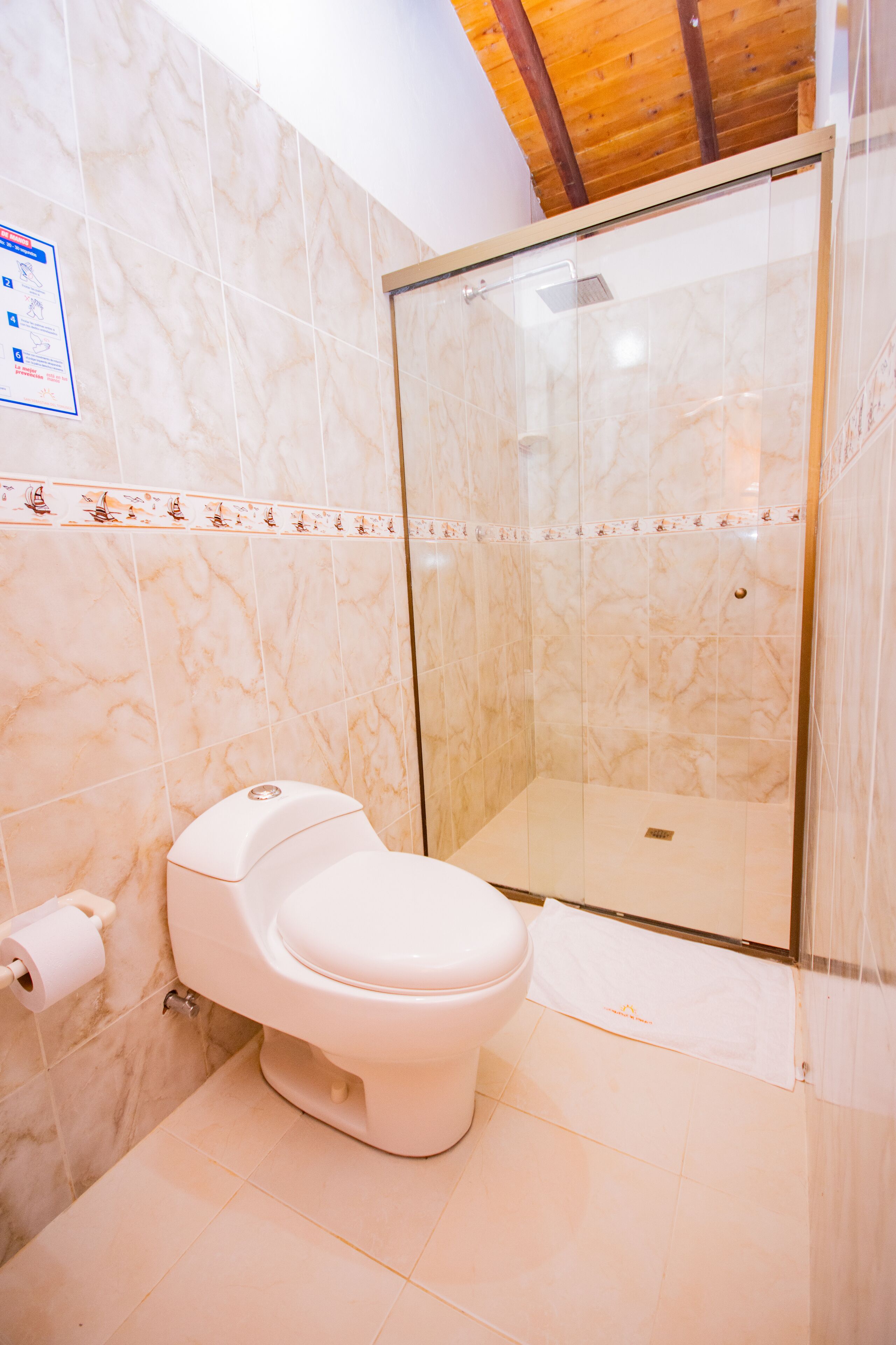 A bathroom with a toilet, a shower enclosure, and a marble wall.