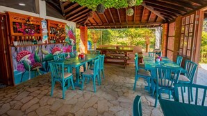 Un espace extérieur aménagé en terrasse, avec des tables et des chaises en bois, entouré d’un plafond et de murs en bois rustique.