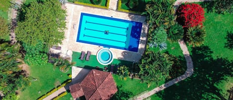 Relax by the serene pool surrounded by lush greenery and tropical plants.
