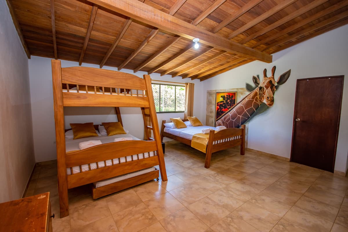 Una habitación con dos literas de madera, un mural de jirafa y una puerta de madera.