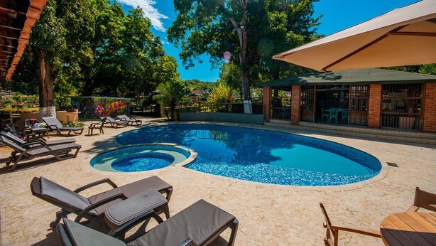 Une piscine avec des chaises longues et un espace abrité.