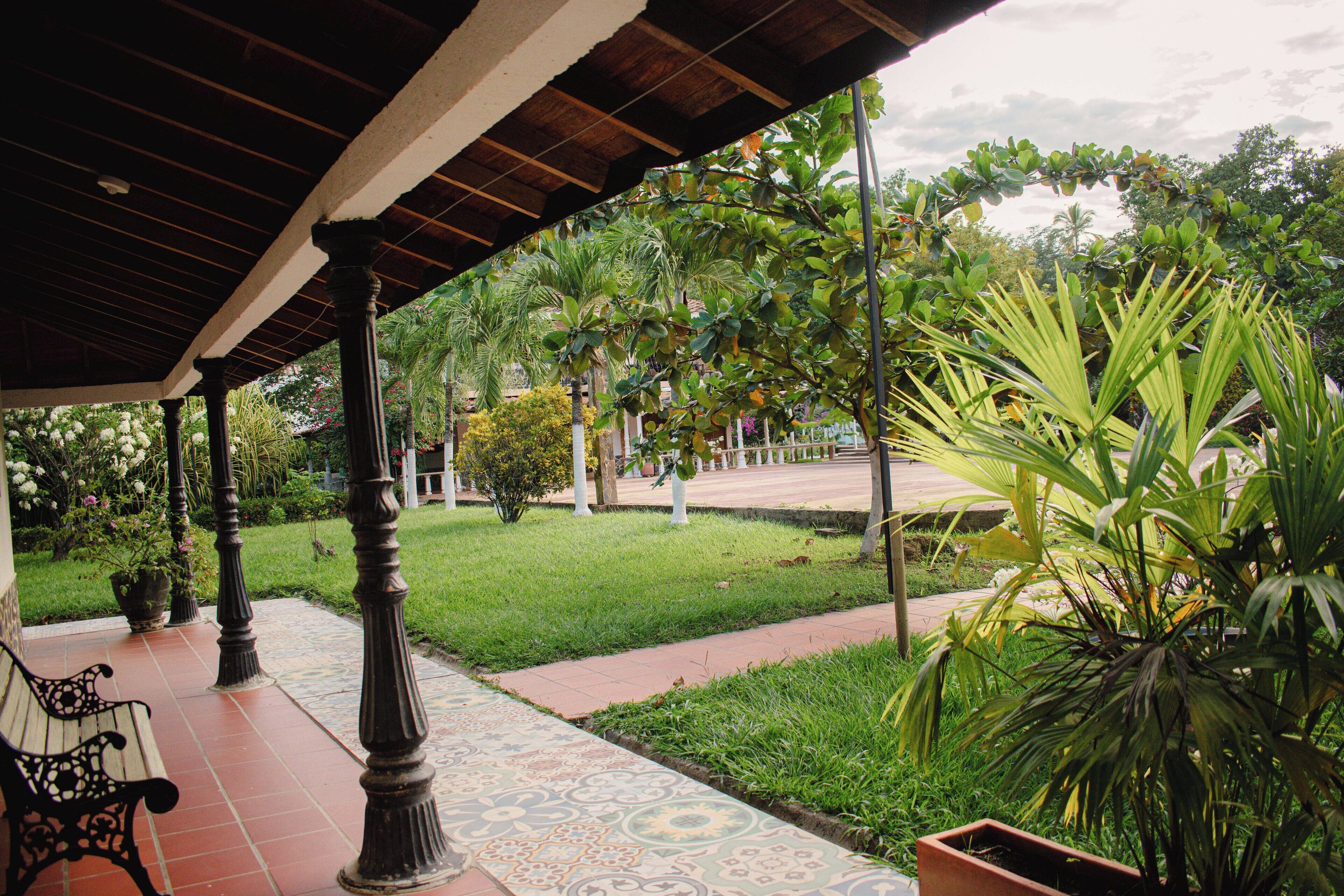 A covered patio area with a patterned floor, a bench, and potted plants.
