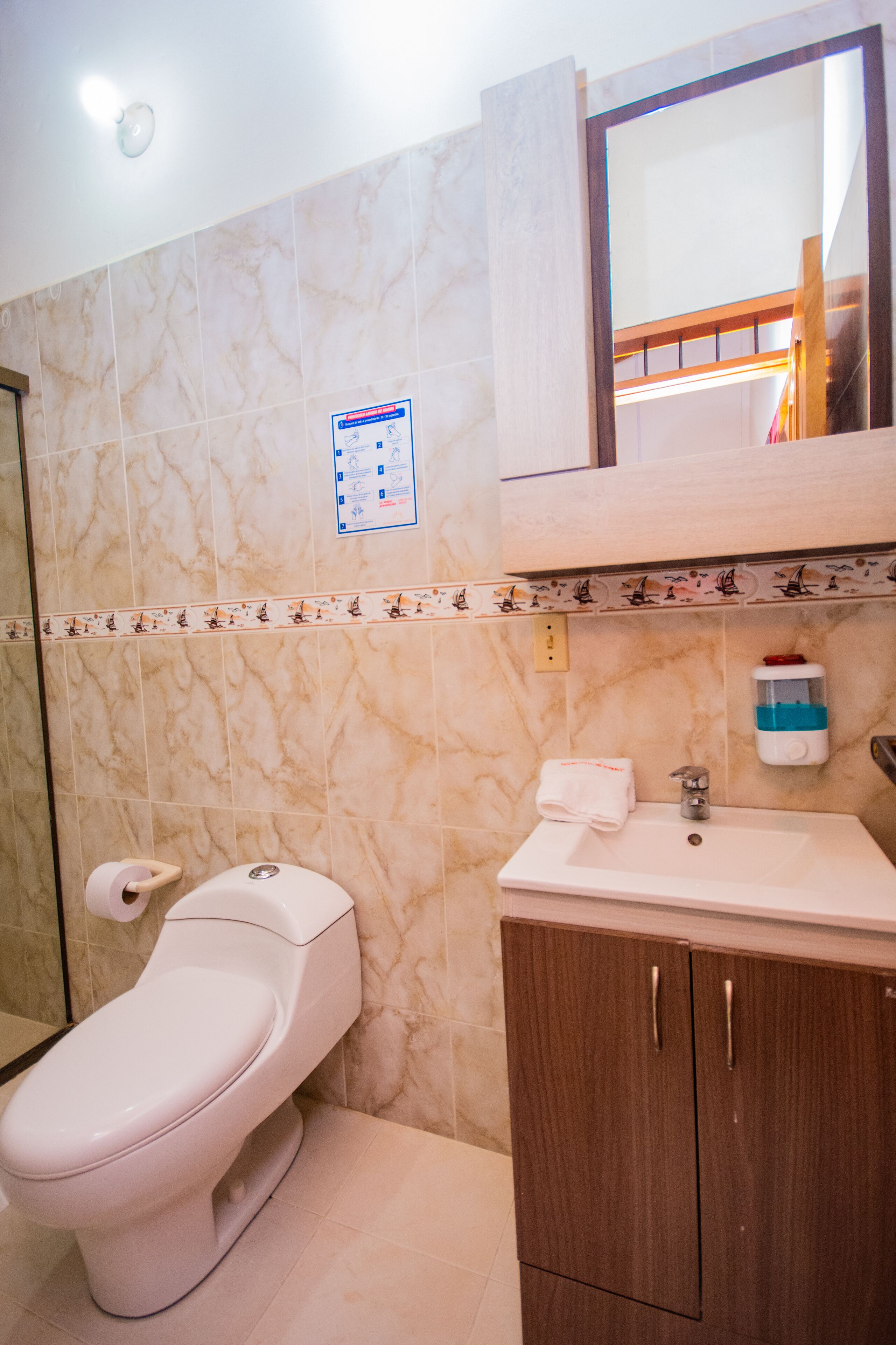A bathroom with a toilet, sink, and mirror.