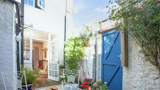 A small outdoor patio with a table and chairs, surrounded by potted plants and a blue door. - 3 bedroom accommodation in Colyton, near Lyme Regis (Colyton, near Lyme Regis)