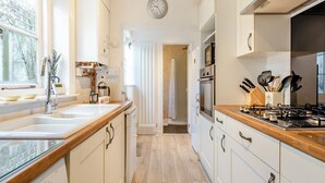 A modern kitchen with white cabinets, stainless steel appliances, and a wooden countertop. - 3 bedroom accommodation in Colyton, near Lyme Regis (Colyton, near Lyme Regis)