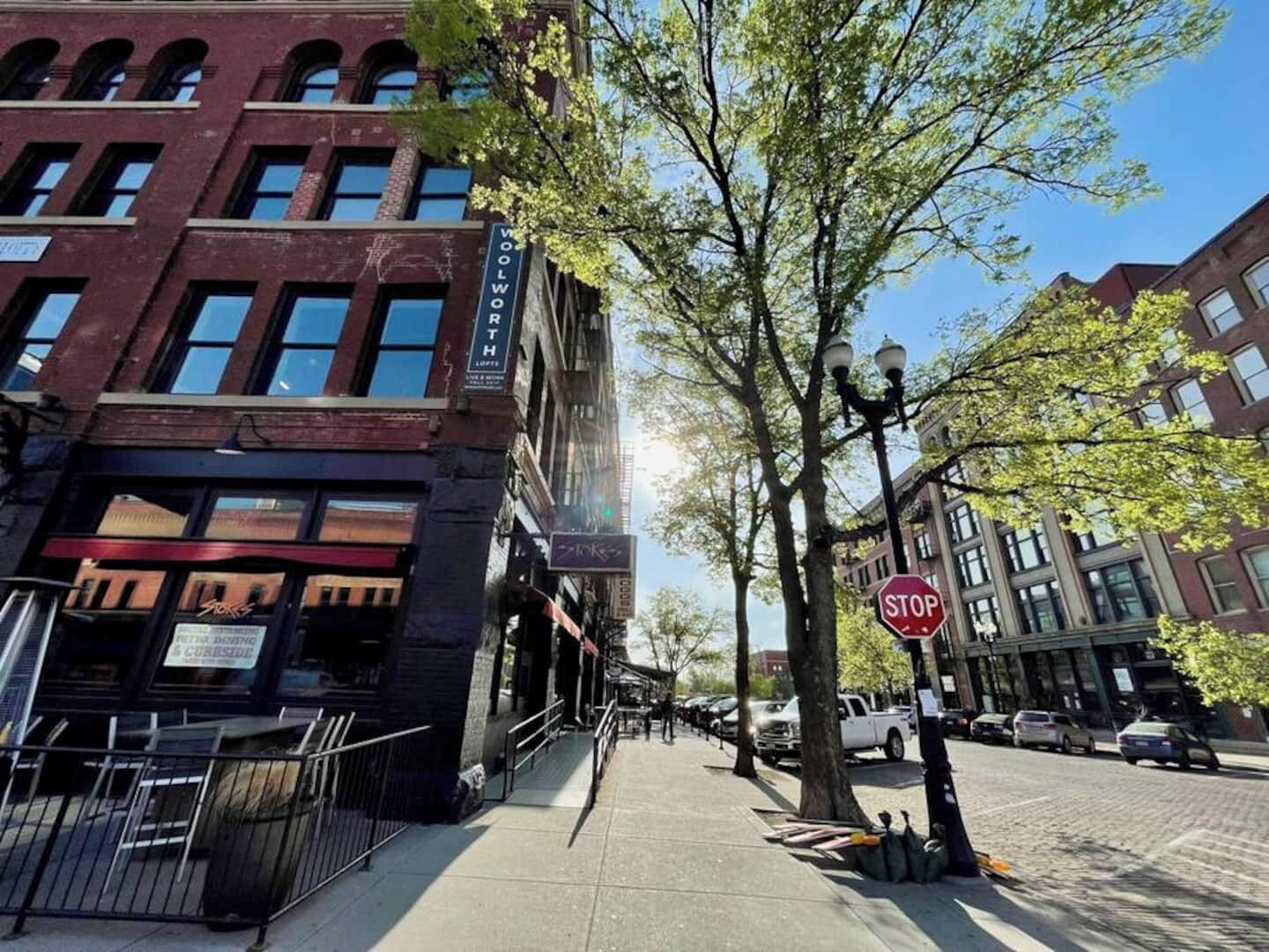 Une vue de rue avec un bâtiment portant l’inscription « WOOLWORTH » et un panneau « STOP ».