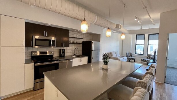 A modern kitchen with stainless steel appliances, a large island, and pendant lighting. - This serviced apartment is a 4 bedroom(s), 4 bathrooms, located in Omaha, NE. (Omaha)