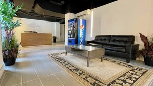 A modern lobby with a reception desk, a Pepsi vending machine, a black leather sofa, and a patterned rug. - This serviced apartment is a 4 bedroom(s), 4 bathrooms, located in Omaha, NE. (Omaha)