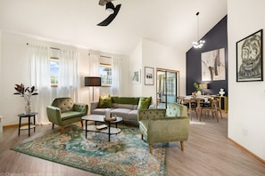 A modern living room with a sofa, armchairs, a coffee table, and a dining area with a table and chairs.