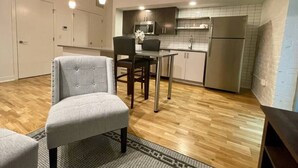 Une cuisine compacte avec un coin repas, un plancher en bois et des luminaires suspendus.