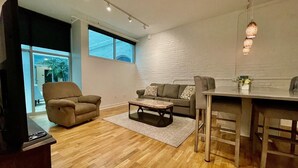 A modern living room with a sofa, armchair, coffee table, and dining area.