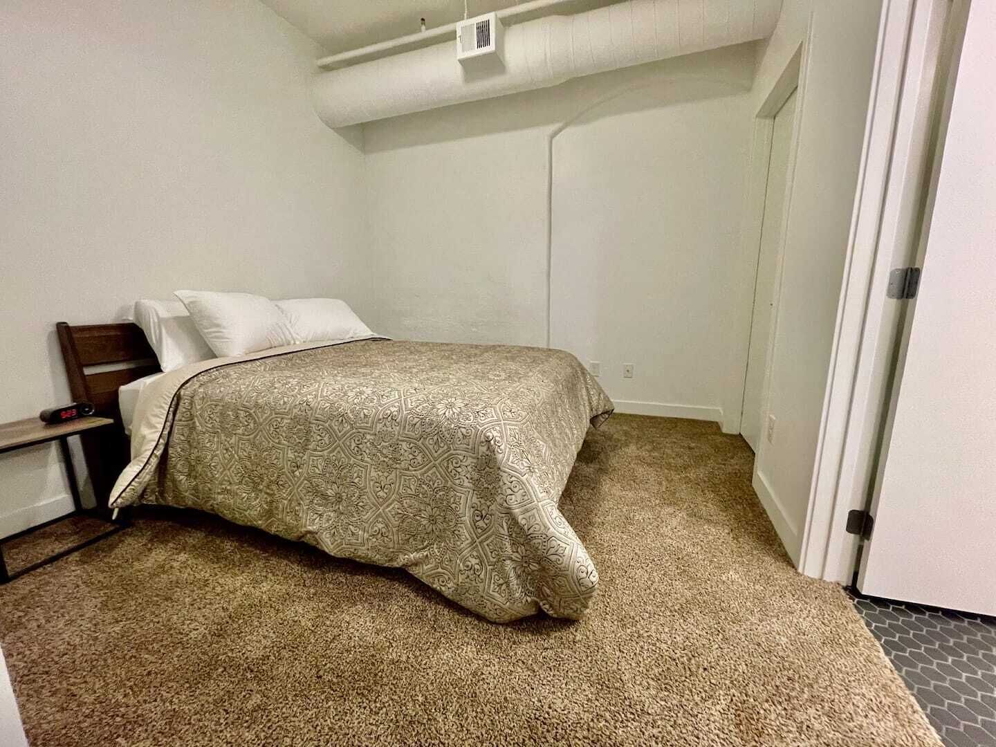 A bedroom with a bed, a nightstand, and a door.