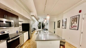 A modern kitchen with stainless steel appliances, a central island, and a dining area with a view of the living room. - A historic movie themed, 1,200 square foot loft in the heart of the Old Market (Omaha)