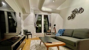 A modern living room with a grey sofa, a wooden coffee table, a TV, and a patterned rug. - A historic movie themed, 1,200 square foot loft in the heart of the Old Market (Omaha)