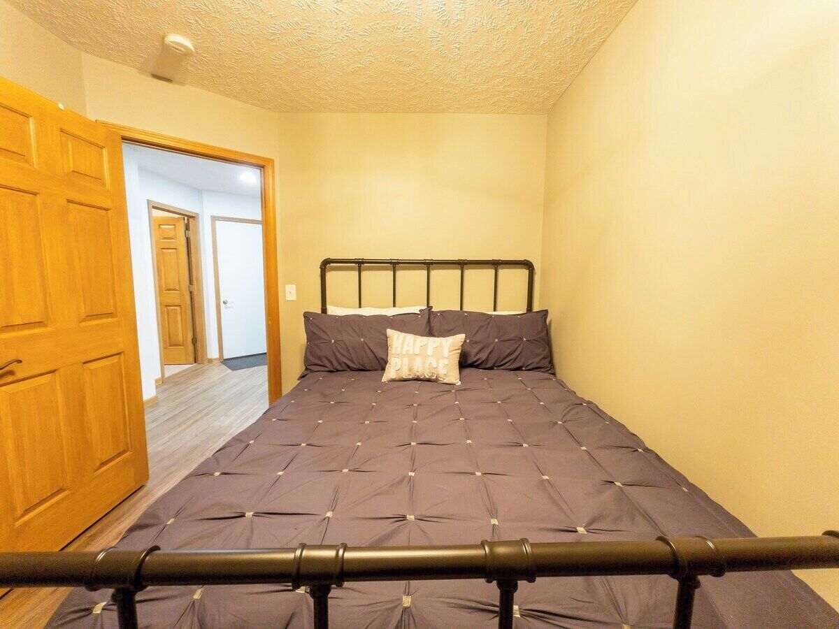 A bedroom with a bed, a wooden door, and a hallway.